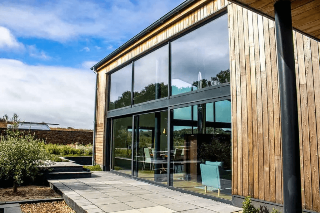 Floor-to-ceiling architectural glazing in a large barn conversion, creating a bright open-plan living space